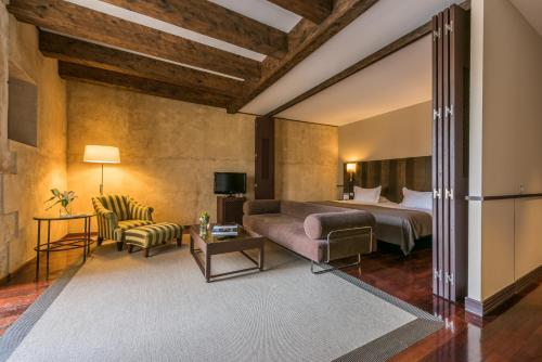 萨拉曼卡圣埃斯特万宫酒店的一间卧室配有一张床、一张沙发和一把椅子