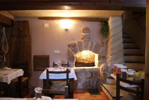 AlcorisaHotel Casa de la Fuente的餐厅设有石制壁炉、桌子和椅子