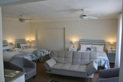普利登堡湾113 on Robberg的酒店客房带两张床、一张沙发和椅子