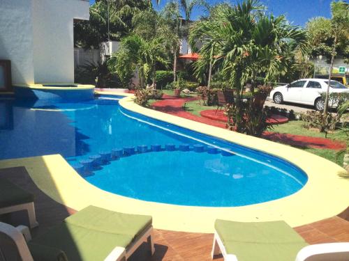 萨尤利塔Hotel y Suites Los Encantos的一个带汽车的院子内的一个大型游泳池