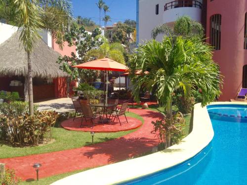 萨尤利塔Hotel y Suites Los Encantos的游泳池旁的天井配有桌子和遮阳伞