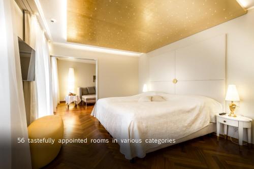 卢塞恩德天平酒店的一间带白色床的卧室和一间带椅子的房间