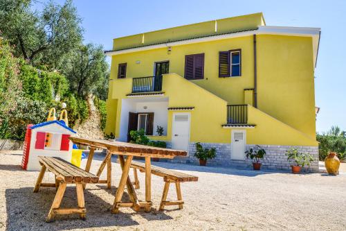 维耶斯泰Alba Del Gargano Home的黄色的房子,设有野餐桌和游乐场