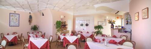 兰佩杜萨法国圣骑士酒店的餐厅配有白色的桌椅和红色的餐巾