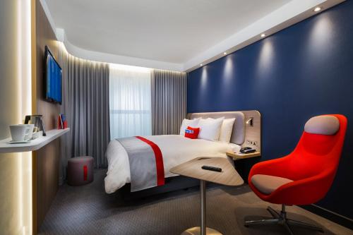圣奥尔本斯Holiday Inn Express St. Albans - M25, Jct.22的酒店客房,配有一张床和一张红色椅子
