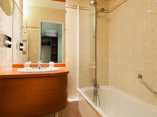 圣皮耶尔代科尔普基里亚德图尔圣皮埃尔库尔车站酒店的浴室配有盥洗盆和浴缸。
