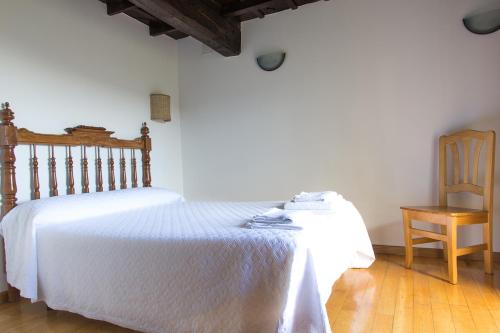 Cerdeira卡萨多考密电特酒店的卧室配有白色的床和木椅