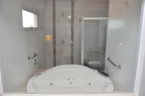 阿拉瓜伊纳帕利斯高级酒店的白色的浴室设有浴缸和淋浴。