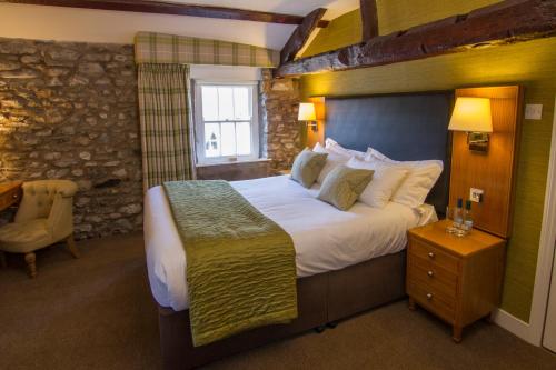 柯比朗斯代尔太阳旅馆的一间卧室设有一张大床和石墙