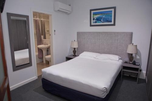 悉尼沙威双湾酒店 的一间带白色大床的卧室和一间浴室