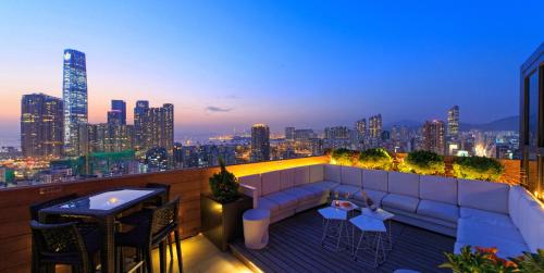 香港木的地酒店  的屋顶庭院配有沙发和桌子,享有城市天际线