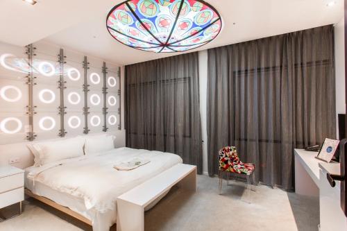 高雄树屋旅店的卧室配有白色的床和吊灯。