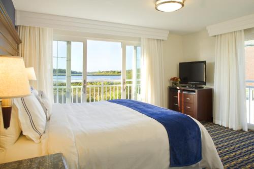 米德尔敦纽波特海滩套房酒店的一间卧室配有一张床、一台电视和一个阳台