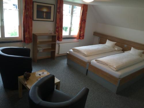 Bütschwil阳光旅馆的酒店客房,配有两张床和椅子