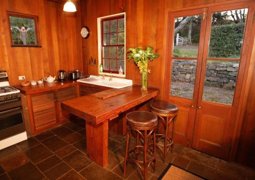 Kurrajong冬宫小屋住宿加早餐旅馆的厨房配有木桌和凳子