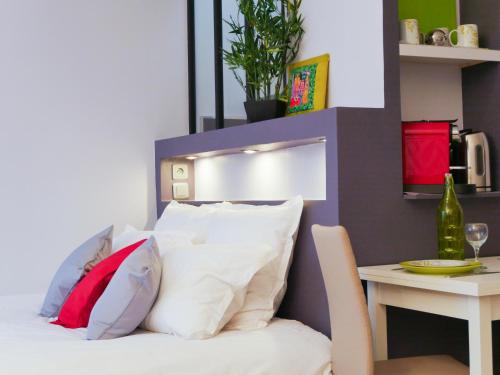图卢兹普尔潘天顶斗牛场尊贵一室公寓的客房配有带枕头和桌子的床。