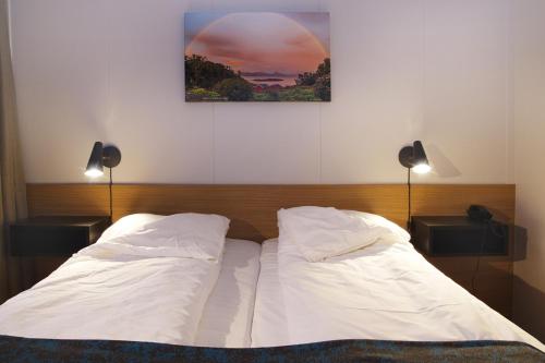 InnhavetHamarøy Hotel的一张带两个白色枕头的床和一张墙上的照片