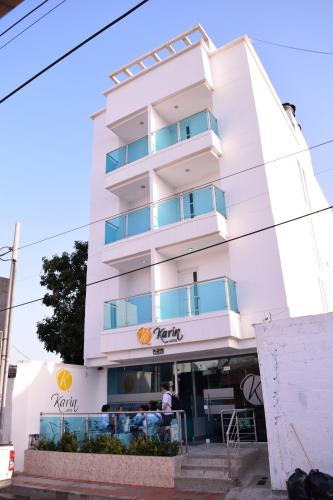 里奥阿查Karin Hotel的一座白色的建筑,前面有一个人站在