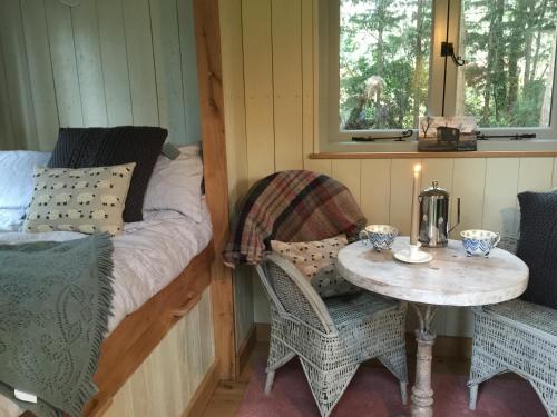 霍尔特Chez Marguerite Luxury Shepherd's Hut的配有一张床和一张桌子及椅子的房间