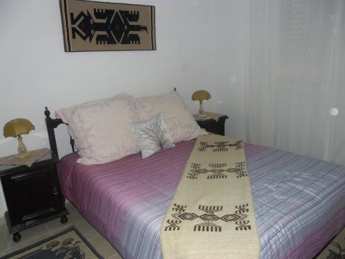 甘达坞伊港Apartment Essayadi Residence的一间卧室配有一张带紫色床单的床和两盏灯。