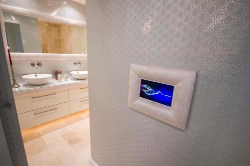 马略卡岛帕尔马帕尔马设计套房酒店 的一间带两个盥洗盆的浴室和墙上的电视