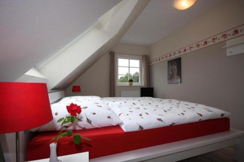 普雷罗Ferienhaus Uhlenhus的卧室设有红色和白色的床和窗户。