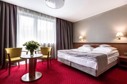 卡尔帕奇Hotel Konradówka Wellness & SPA - 300 metrów do centrum的酒店客房带一张床、一张桌子和椅子