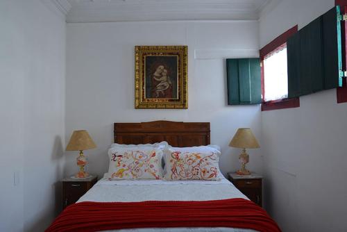 欧鲁普雷图Pousada Guignard的一间卧室配有一张带两盏灯的床,墙上挂着一张照片