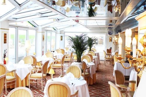库克斯港司图茨公寓式酒店 - 斯坦普乐酒店的餐厅设有白色的桌椅和窗户。