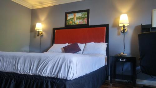 奥兰治大A汽车旅馆 的一间卧室配有一张带白色床单和两个灯的大床