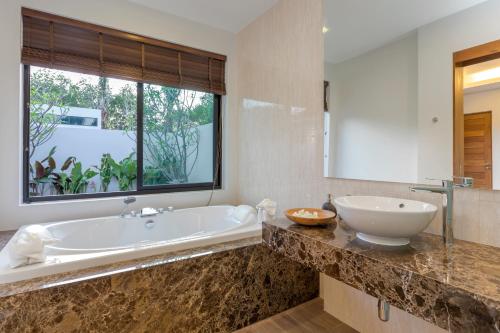奈扬海滩普吉岛泳池别墅的带浴缸的浴室和大窗户
