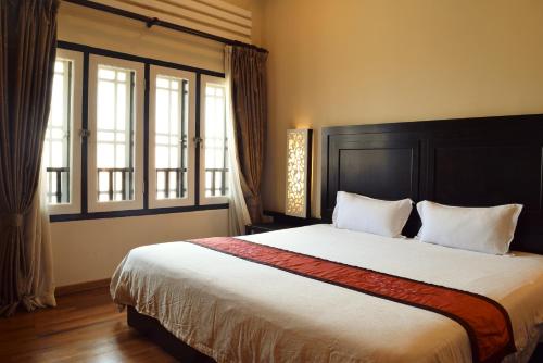 马六甲马六甲鸡场街精品酒店的一间卧室设有一张大床和两个窗户。
