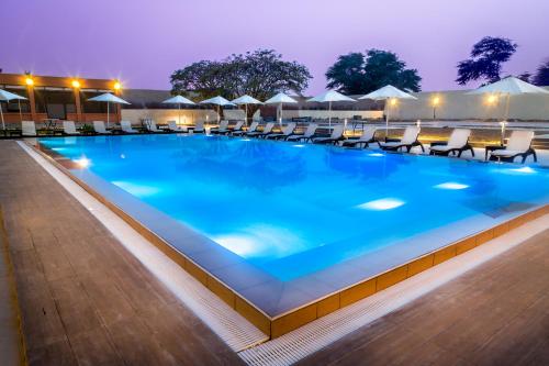 努瓦克肖特Azalaï Hôtel Nouakchott的夜间游泳池,配有椅子和遮阳伞