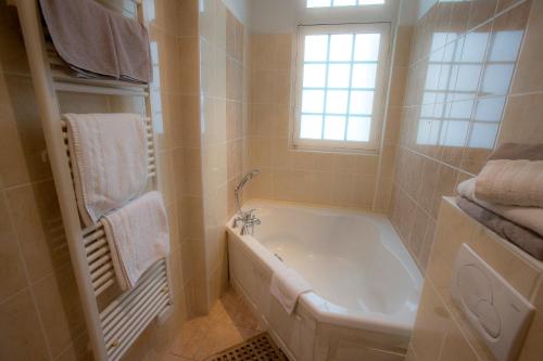 多维尔Villa Augeval Hôtel de charme & Spa的带浴缸的浴室和窗户。