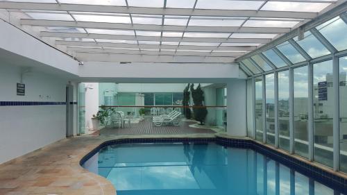 瓜鲁雅Apartamento Temporada Guarujá Four Seasons的一座室内游泳池,位于一座带窗户的建筑中