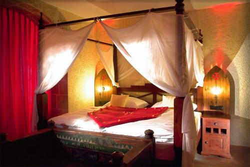 宾茨韦希特尔滨兹酒店的一间卧室配有一张带红色窗帘的天蓬床