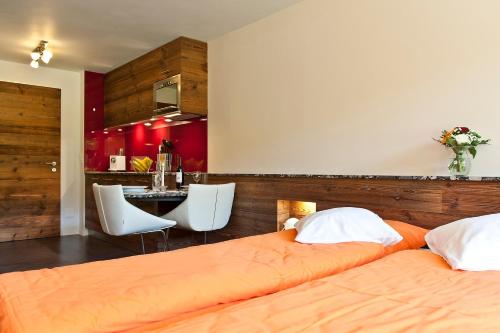 采尔马特Studio Castor Zermatt的一间带两张床的卧室和一间带红色墙壁的厨房