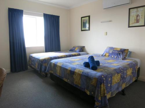 飞鱼湾VQ3山林小屋的一间卧室设有两张带蓝色床单的床和窗户。