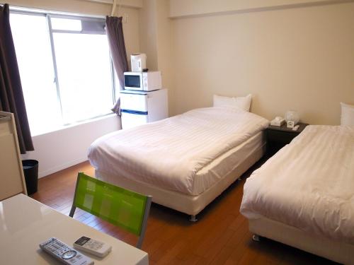 洲本市水母岛公寓的酒店客房设有两张床、一张桌子和一个窗户。