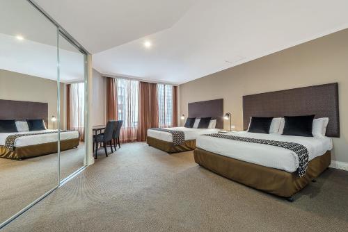 墨尔本小柏克街曼特拉酒店的酒店客房配有两张床和一张书桌