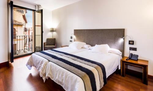 格拉纳达Monjas del Carmen Hotel的一间设有大床和窗户的酒店客房
