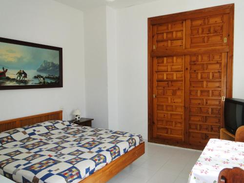 阿桂拉斯Los Geraneos的一间卧室配有一张床、一台电视和一扇门