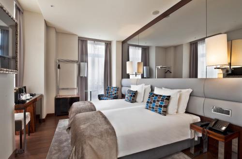 里斯本宫殿广场特里姆酒店的酒店客房设有一张大床和一张书桌。