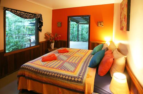 Mena Creek热带极乐住宿加早餐旅馆的一间卧室拥有橙色的墙壁,配有一张带枕头的床。