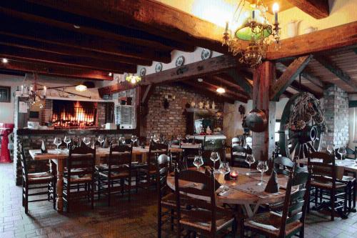 泽伊恩克尔克多福斯特餐厅酒店的餐厅设有木桌、椅子和吊灯。