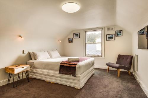 霍巴特宾顿度假屋的一间卧室设有一张床、一个窗口和一把椅子