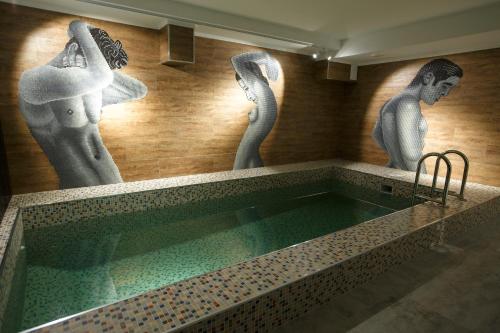彼得罗巴甫洛夫斯克格林威奇酒店的墙上有女雕像的游泳池
