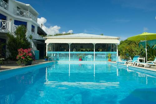 哥西尔Hotel Cap Sud Caraibes的一座游泳池,毗邻一座建筑,设有凉亭