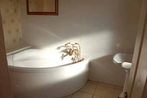 彭布罗克中门酒店的白色的浴室设有浴缸和水槽。