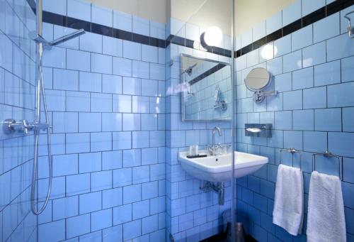 海尔德罗普奈维尔酒店的蓝色瓷砖浴室设有水槽和淋浴